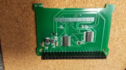 A circuit board with integrated circuits and a pin header on a cork surface.