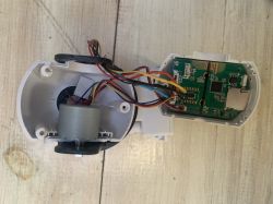 Open casing of an electronic device showing a circuit board and a small motor.