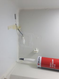 Wymieniony czujnik w zamrażarce z widoczną hermetyczną instalacją.