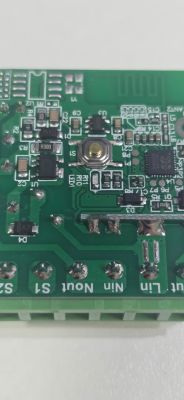 Close-up of a PCB with push button, chips, and labeled terminal blocks