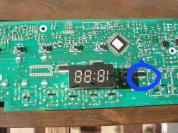 Washing machine PCB with non-functional IC6 component circled in blue.