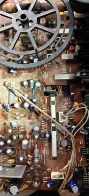 Wnętrze starego magnetofonu Hitachi z widoczną płytą główną i kondensatorami.