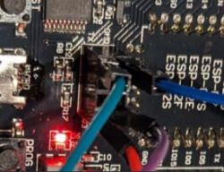 Close-up of an ESP board with connected wires, and a lit red LED.
