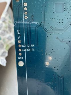 Close-up of a printed circuit board showing test points UART2_RX, UART2_TX, and GND, with a PS_3V3 marking.