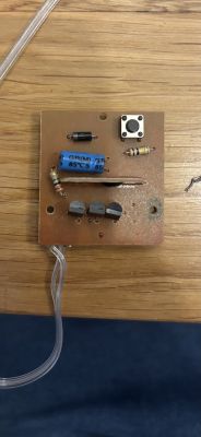 Płytka PCB z kondensatorem, przyciskiem, trzema tranzystorami i rezystorami.