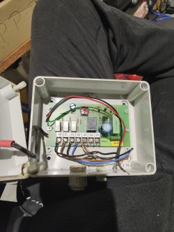 Otwarta plastikowa obudowa z zamontowaną płytką elektroniki i podłączonymi przewodami.