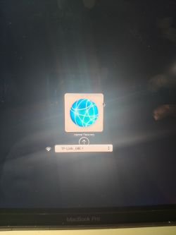 Ekran MacBooka Pro z wyświetloną ikoną obracającego się globusa i napisem Internet Recovery, poniżej widoczna jest lista dostępnych sieci Wi-Fi.