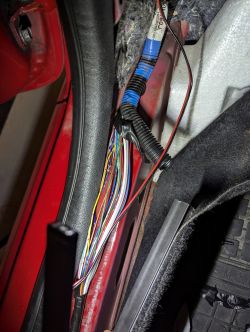 Wiązka przewodów w drzwiach samochodu, z widocznymi kolorowymi kabelkami