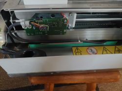 Wnętrze maszyny z widoczną płytką elektroniczną i okablowaniem.