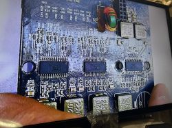 Zbliżenie na płytkę PCB z komponentami elektronicznymi, w tym układami scalonymi i kondensatorami.