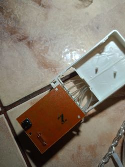 Płytka elektroniki z przyciskiem i przewodami wewnątrz plastikowej obudowy