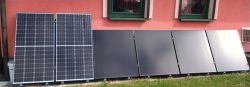 Panele słoneczne zainstalowane przy ścianie budynku pod oknami na trawie