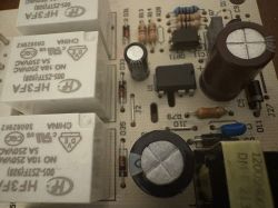 Zbliżenie na płytkę PCB z przekaźnikami, kondensatorami elektrolitycznymi i układem w obudowie DIP