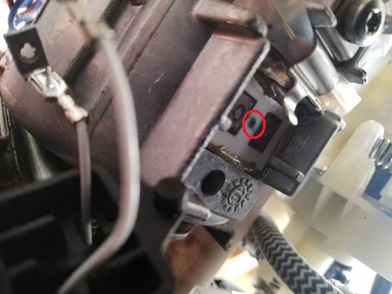 Zbliżenie na część mechaniczną z czerwonym kółkiem wokół małego oznaczenia.