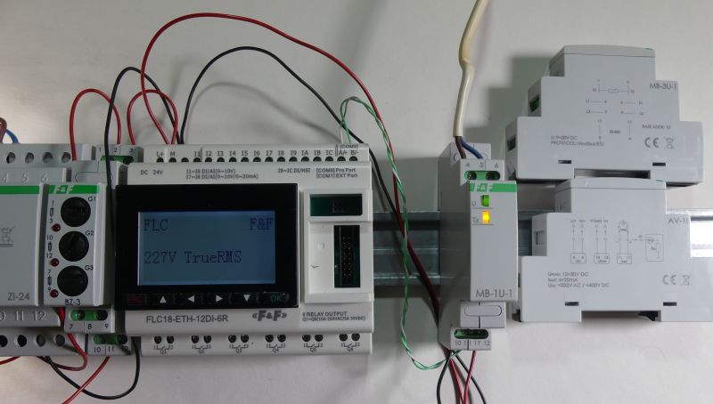 Sterownik logiczny F&amp;F podłączony do modułów automatyki na szynie DIN z wyświetlaczem LCD pokazującym napięcie 227V TrueRMS.