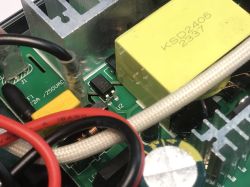 Zbliżenie na wnętrze stacji lutowniczej, widoczne elementy elektroniczne, przewody i radiator.
