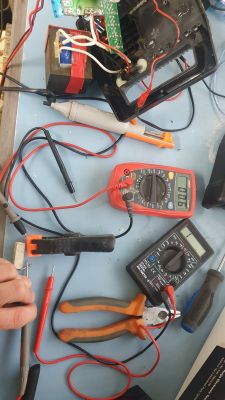 Zestaw narzędzi elektrycznych i dwa mierniki na stole roboczym.