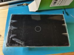 Black rectangular touch panel with a centered circle, covered in protective film