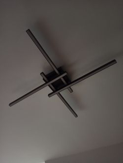 Nowoczesna lampa LED na suficie z czterema długimi ramionami.