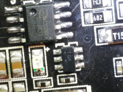 Chip oznaczony TGF z 6 wyprowadzeniami obok układu CS5090E na czarnej płytce PCB