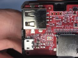 Close-up of a red PCB inside a device, with an HDMI port, micro-USB connector, and microSD card slot