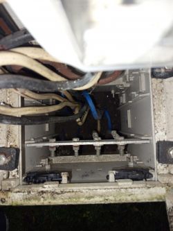 Wnętrze skrzynki elektrycznej z kilkoma kablami różnego koloru.