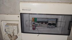 Rozdzielnica elektryczna z plombą, widoczne wyłączniki Eaton i ręczne opisy na osłonie