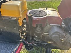 Widok silnika traktorka Husqvarna z otwartą maską, widoczne przewody i obudowa filtra powietrza.