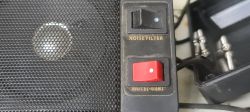Widok dwóch przełączników podpisanych „NOISE FILTER” i „MUTE -8dB” obok głośnika.