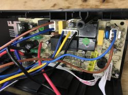 Inside a UPS: circuit board with relays, capacitors, and many colorful wires connected to white plugs