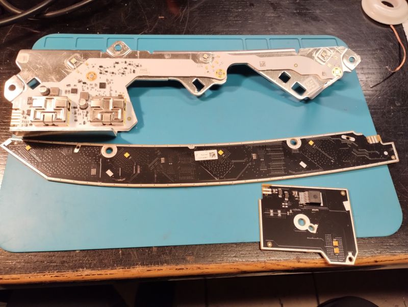 Płytki PCB z układem LED przedniej lampy samochodowej Skoda Fabia IV rozłożone na niebieskiej macie serwisowej.
