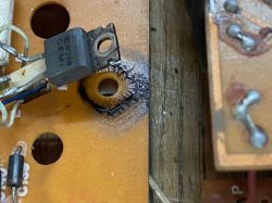 Zbliżenie na płytkę PCB z tranzystorem i śladami zabrudzeń wokół otworu montażowego