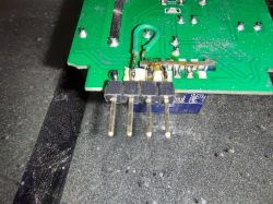 Close-up of a green printed circuit board with protruding pins.