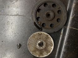 Two dirty components from a Krups coffee machine on a black surface.