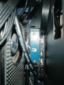 Wnętrze komputera z widocznymi kablami, kartą graficzną i modułem SSD NVMe.