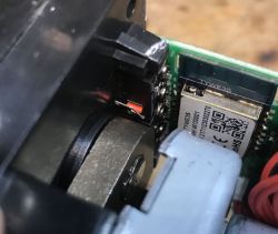 Close-up of an electronic component with a visible control button and a board with a QR code.