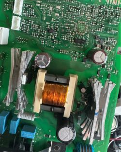 Zbliżenie na zieloną płytkę PCB z cewką, kondensatorami i aluminiowymi radiatorami