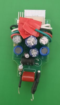 Small PCB with capacitors, colored wires, and red components on a green background
