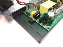 Fragment wnętrza zasilacza impulsowego stacji lutowniczej, widoczny kondensator elektrolityczny, mostek prostowniczy, dławik i elementy filtrujące na zielonej płytce PCB.