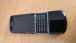 Rozsunięty telefon Nokia z klawiaturą numeryczną, leżący na drewnianym blacie.