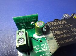 Close-up of a PCB with a FANTAR relay, electrolytic capacitor, and green screw terminal block