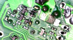 Nahaufnahme einer grünen Leiterplatte mit elektronischen Bauteilen, einschließlich Widerständen und Transistoren.
