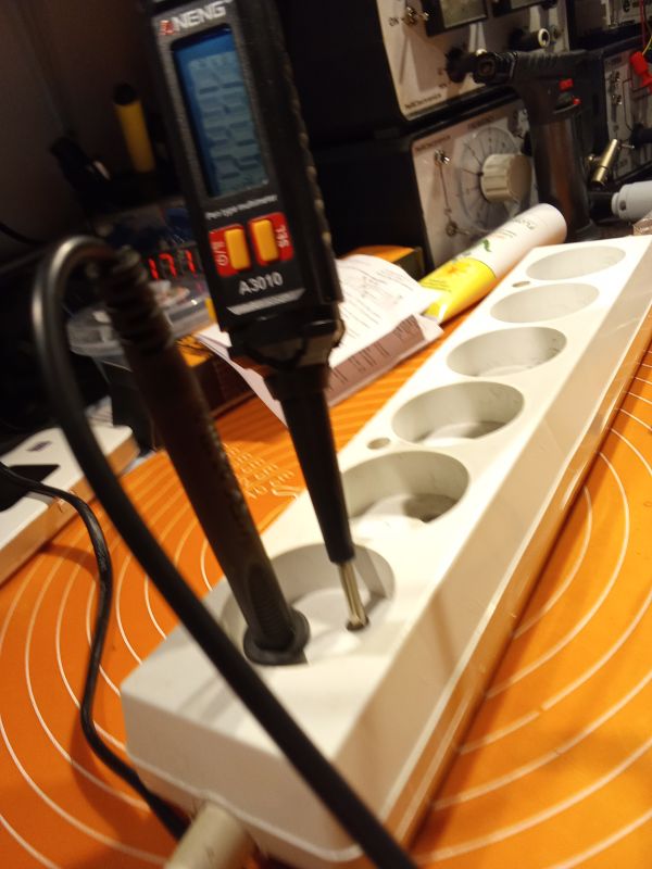 Miernik elektryczny Aneng podczas pomiaru w listwie zasilającej.