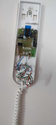 Otwarty panel domofonu z widocznymi kolorowymi przewodami i elektroniką.