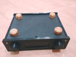 Black electronic enclosure with copper feet and control knobs on light flooring