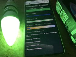 Controlling Tuya LED Bulb via Web Interface with OpenLN882H Firmware A green-glowing Tuya LED bulb next to a smartphone showing the OpenLN882H web interface for LED brightness and color control.