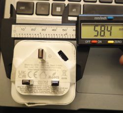 UK smart plug measured with digital caliper, display shows 58.4 mm