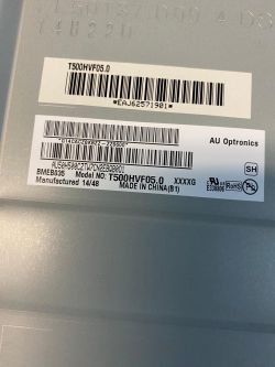 Label with barcodes and model number T500HVF05.0 on a gray metallic surface.