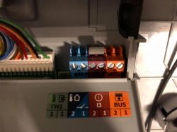 Zbliżenie na moduł elektryczny z przewodami i złączami, w tym na brązową kostkę.