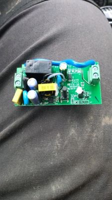 Image of a Sonoff electronic board on black pants, showing various components.